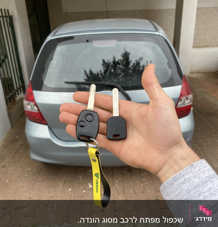 מפתחות רכב ביד מול מכונית חונה